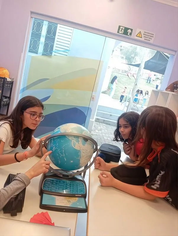 Estudantes do Fundamental 2 observam e discutem um globo terrestre em atividade de projeto na Escola Lumiar Poços de Caldas
